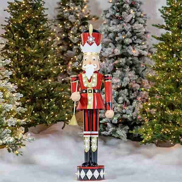 Nutcracker statue against festive Christmas tree background.